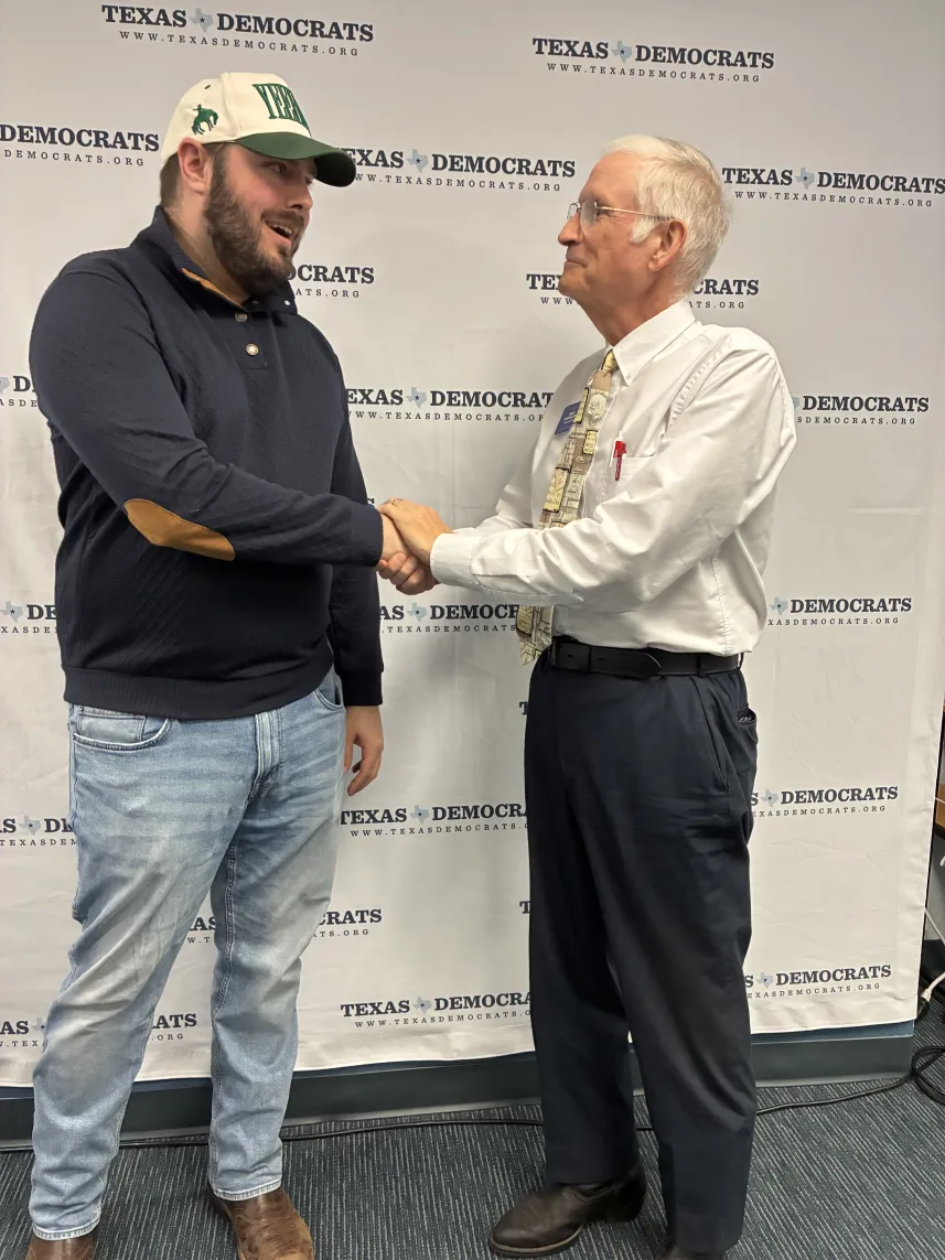 Two men shaking hands in front of a branded backdrop.
