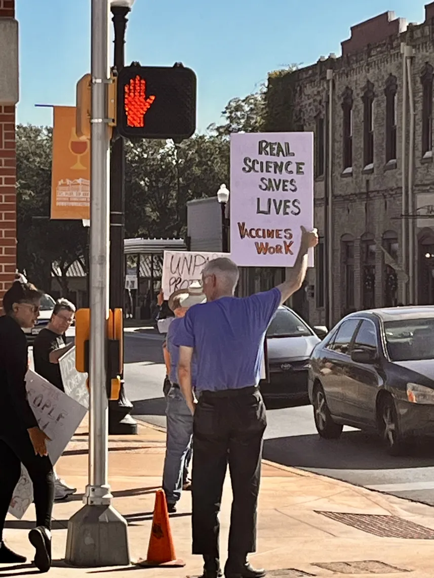 Man holding a sign about justice at a city street corner.