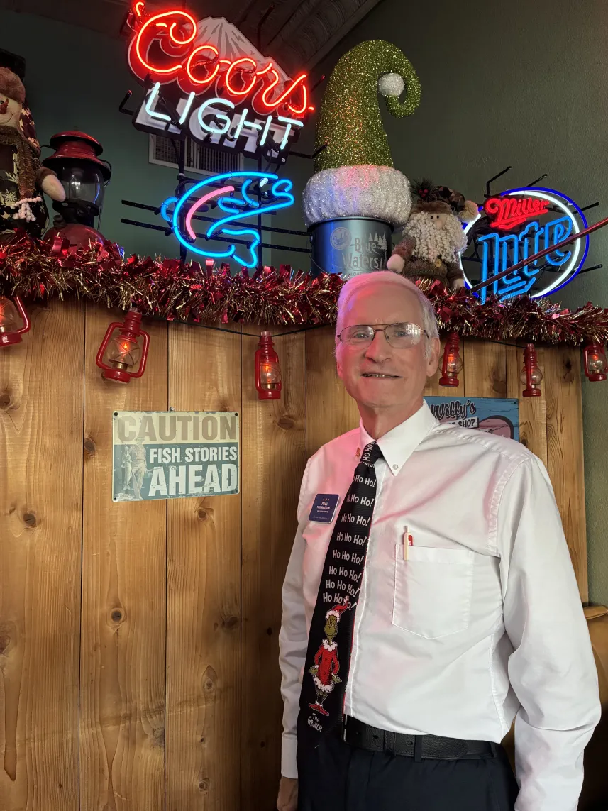 Man in festive tie beside neon beer signs