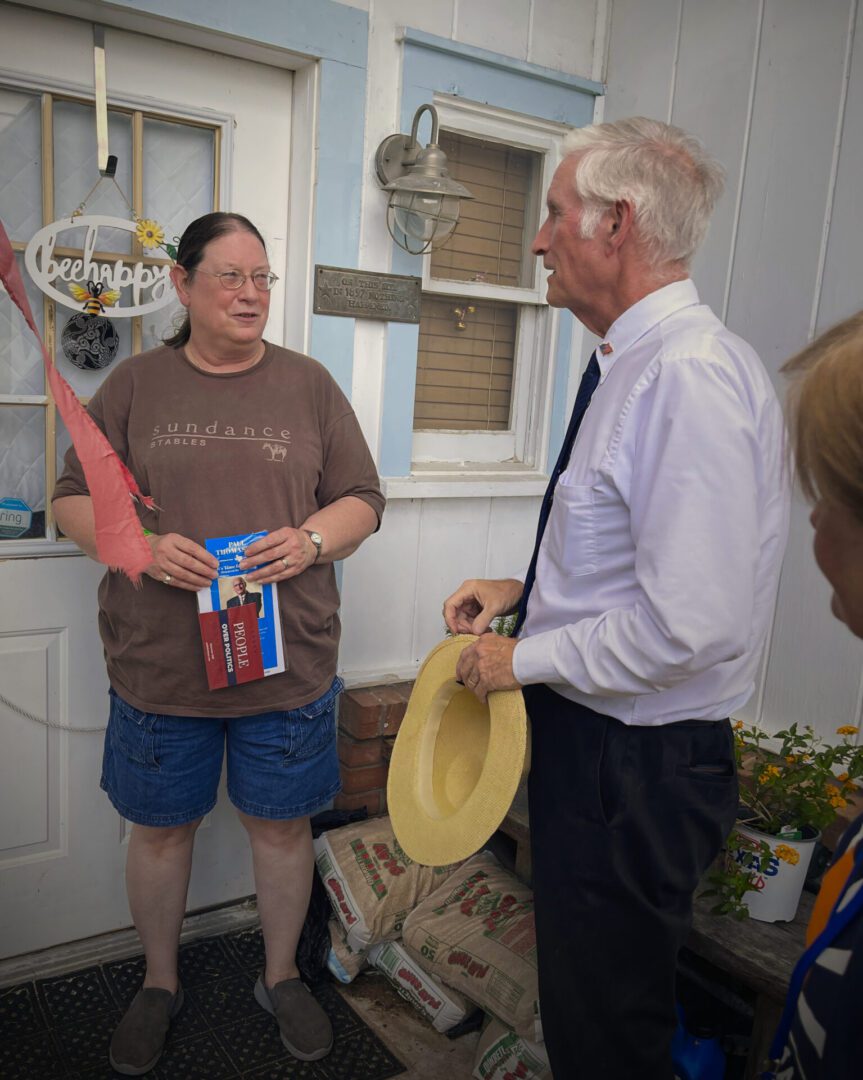 Man with hat talking to homeowner at doorway