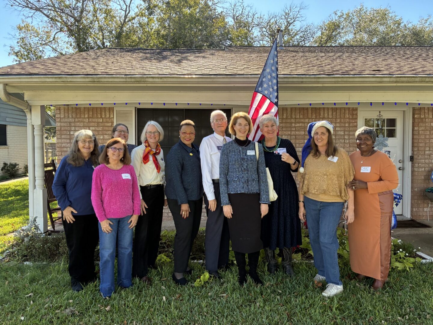 Smiling group by house with American flag